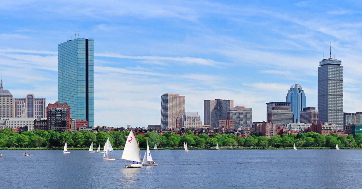 Boston Charles River panorama with urban city skyline skyscrapers and boats with blue sky.